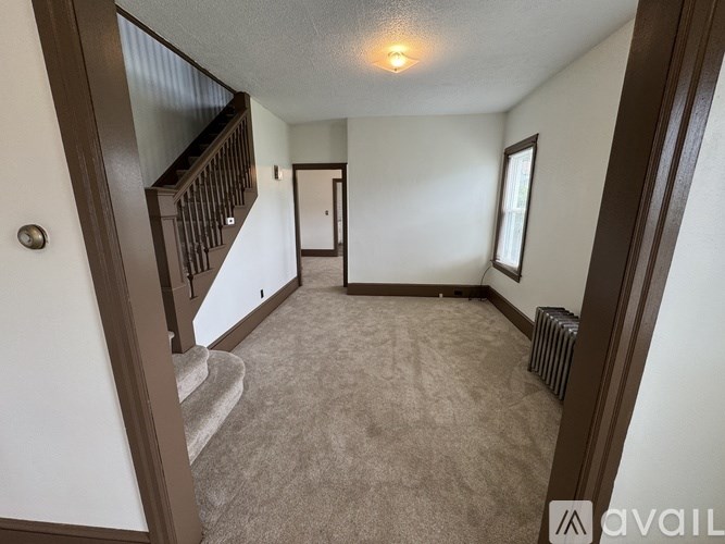 A room with a carpeted floor and a staircase with a railing.