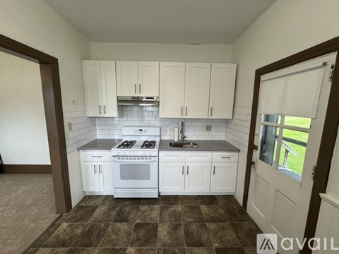 A kitchen with white cabinets and a checkered floor.