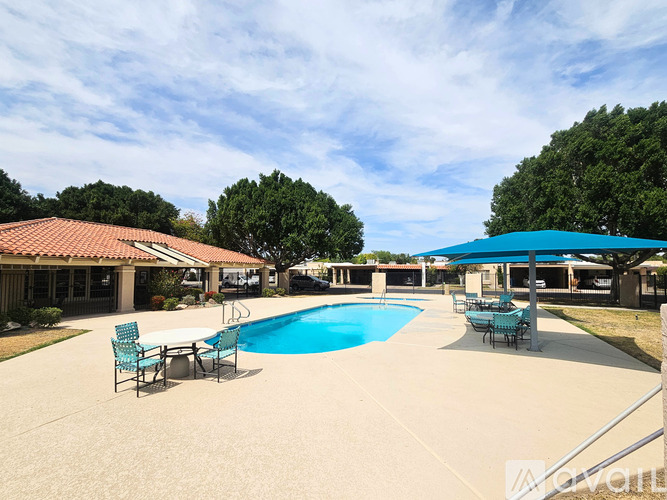 A pool area with a table and chairs and a building in the background.