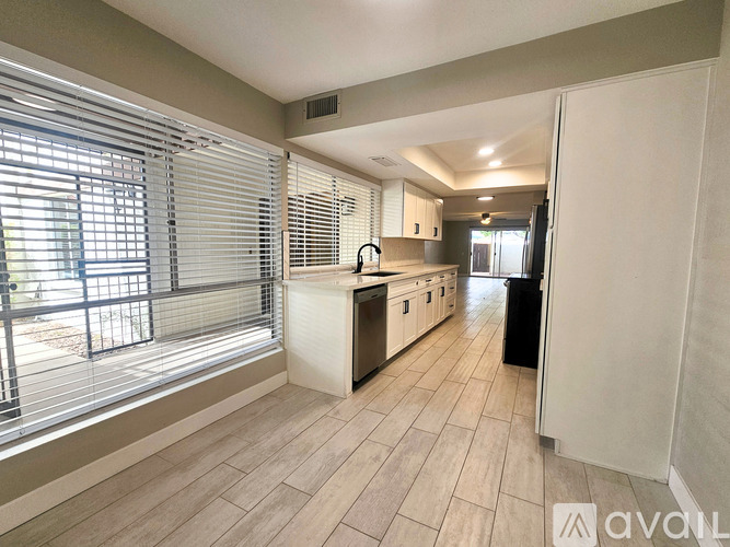 A kitchen with a white counter and a black trash bin.