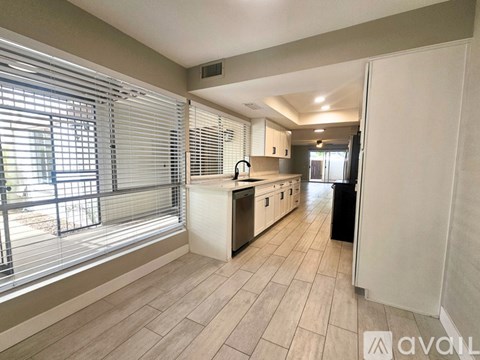 A kitchen with a white counter and a black trash bin.