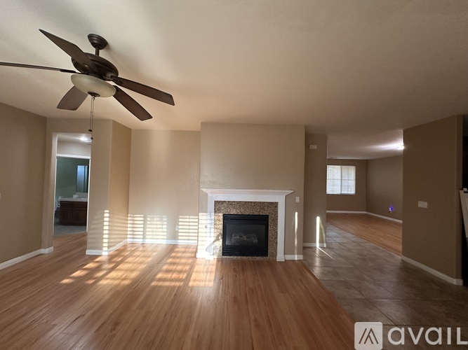 A spacious living room with a fireplace and a ceiling fan.
