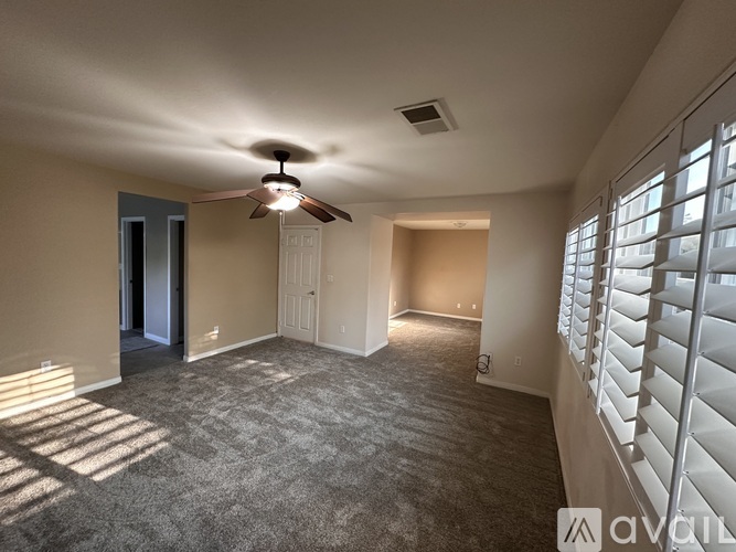 A spacious room with a ceiling fan and carpeted floor.