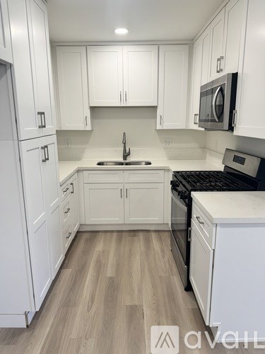 A kitchen with white cabinets and a wooden floor.
