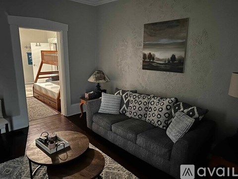 A living room with a grey couch, a coffee table, and a painting on the wall.