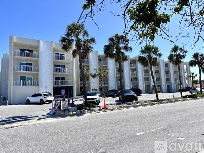 A white building with balconies and cars parked in front.