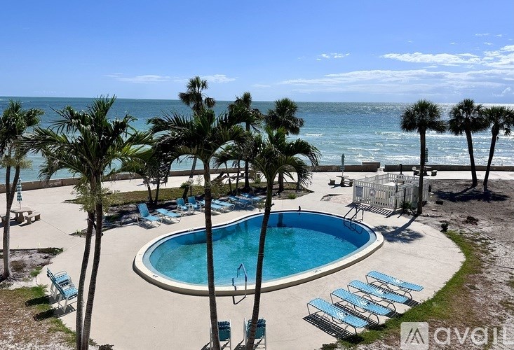 A pool surrounded by palm trees and beach chairs.