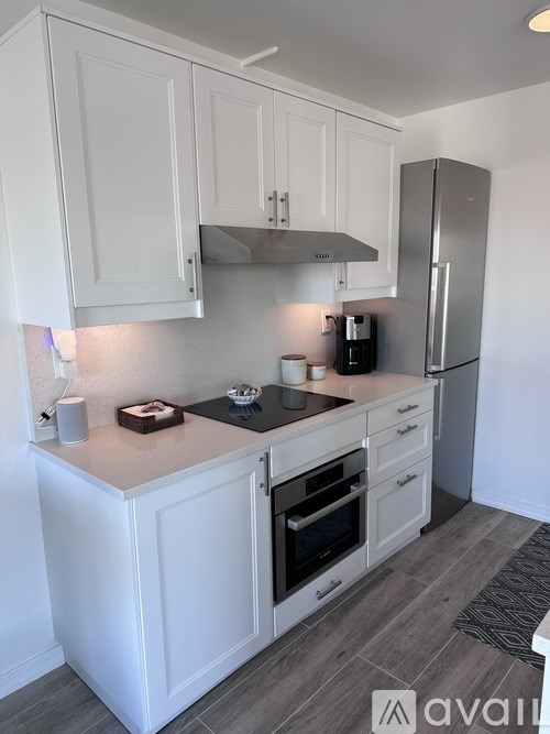 A kitchen with white cabinets and a stainless steel refrigerator.
