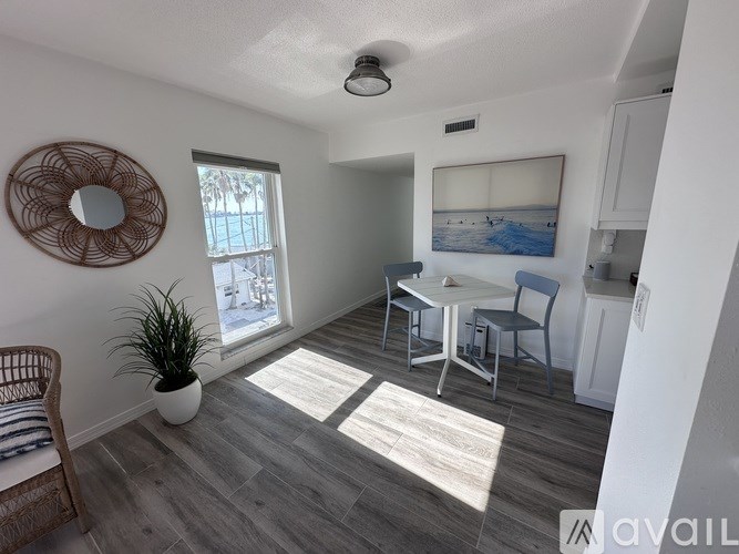 A room with a round mirror on the wall and a potted plant on the floor.