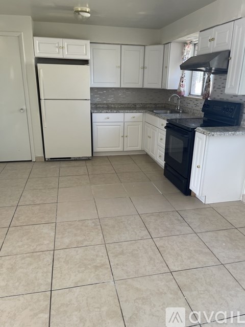 A kitchen with white cabinets and appliances.