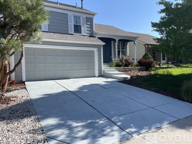 A house with a grey garage door and a white driveway.