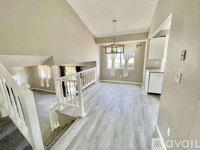 A well-lit, spacious living room with a staircase on the left and a kitchen area on the right.