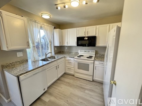 A kitchen with white cabinets and a granite countertop.