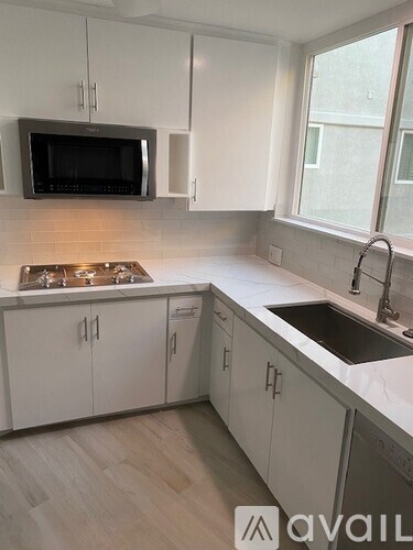 A kitchen with white cabinets and a black microwave.