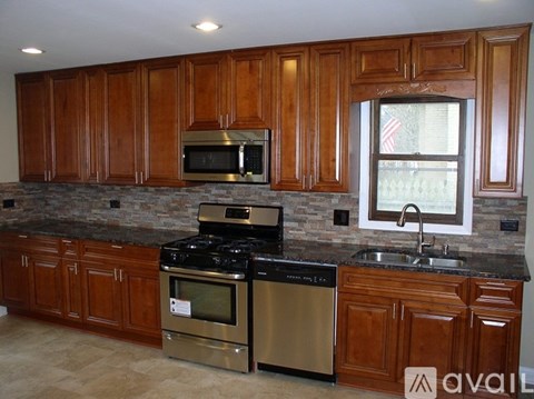 A kitchen with wooden cabinets and a stone backsplash.