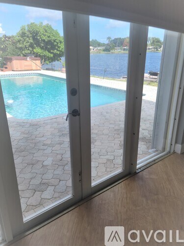 A view of a pool through a sliding glass door.