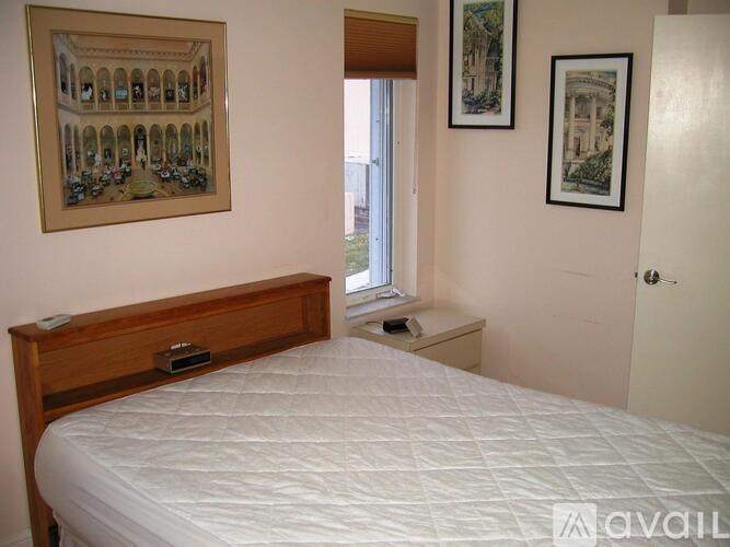 A bedroom with a large bed and two pictures on the wall.