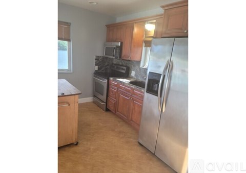 A kitchen with wooden cabinets and a stainless steel refrigerator.