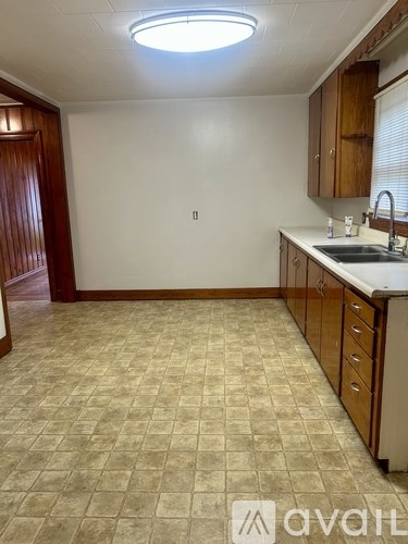 A kitchen with a tile floor and wooden cabinets.