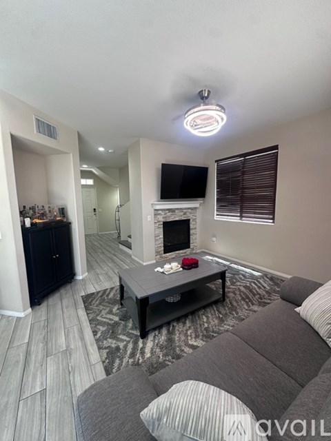 A living room with a grey couch and a fireplace.