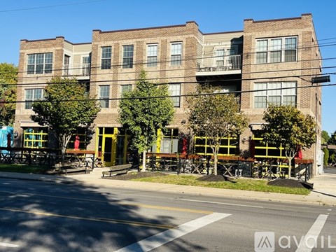 A street view of a multi-story building with a balcony on the second floor.