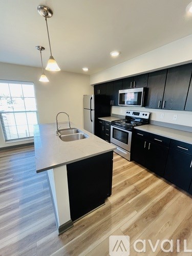 A kitchen with black cabinets and a white island.