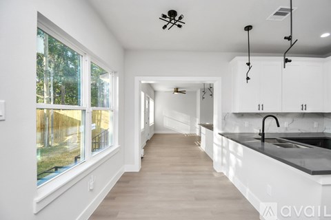 A modern kitchen with white cabinets and a black countertop.
