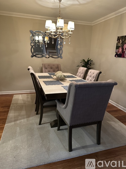A dining room with a table set for two and a chandelier hanging from the ceiling.
