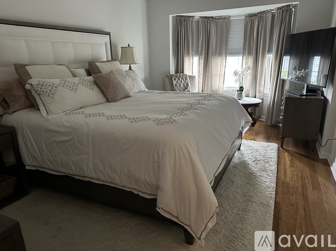 A bedroom with a large bed and a window with curtains.