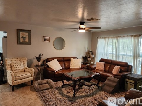 A living room with a brown leather couch, a chair, and a coffee table.