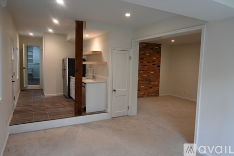 A kitchen area with a refrigerator, microwave, and a countertop with a wooden column in the middle.