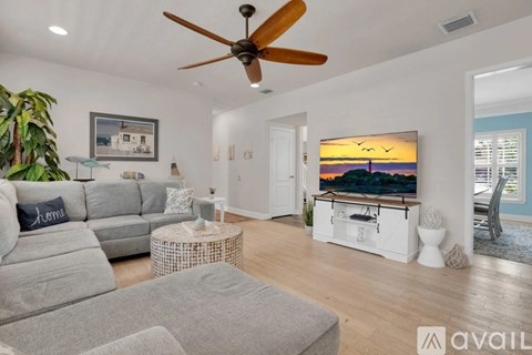 A living room with a grey sofa and a ceiling fan.