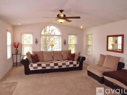 A living room with a checkered sofa and a fan.