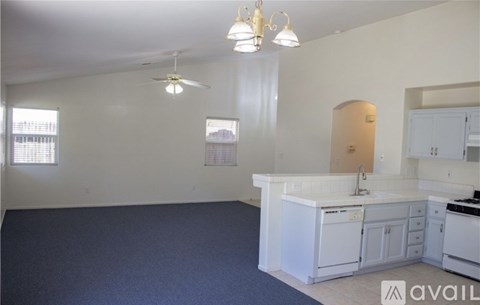A kitchen with white cabinets and a blue carpet.