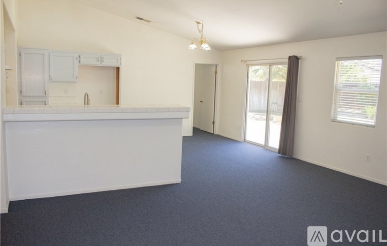A spacious room with a kitchenette and sliding glass doors leading to a balcony.