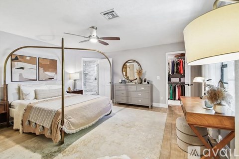 A bedroom with a four poster bed and a rug on the floor.