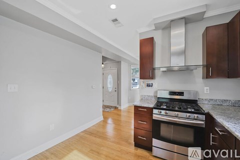 A kitchen with a stove top oven and wooden floors.