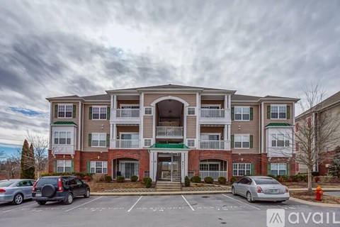 A large apartment building with a parking lot in front.