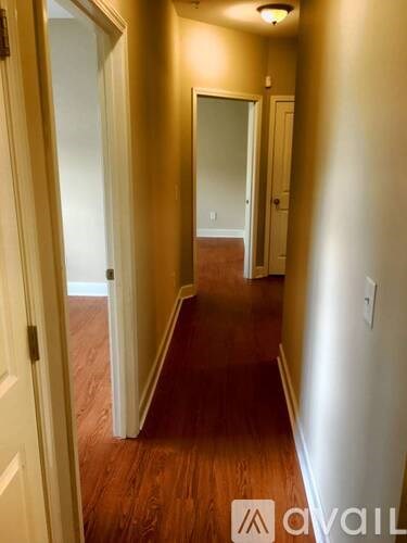 A hallway with a wooden floor and white walls.