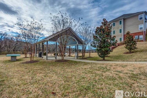 A gazebo-like structure sits in the middle of a grassy area with apartment buildings in the background.