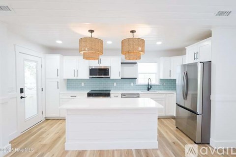 A kitchen with white cabinets and a white island.