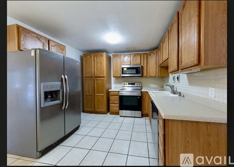 A kitchen with a refrigerator, microwave, oven, and cabinets.