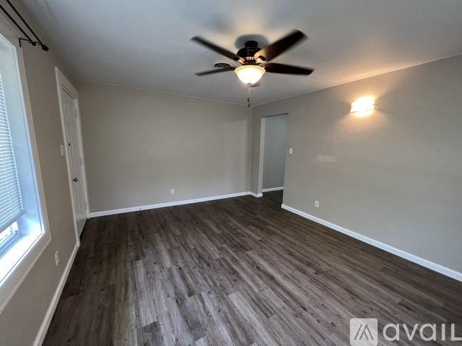 A room with a ceiling fan and wooden flooring.