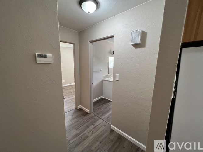 A hallway with a door on the right and a wall-mounted air conditioner on the left.