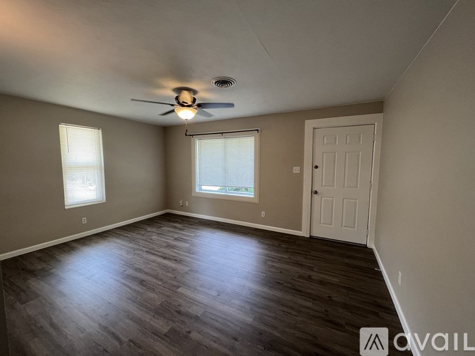 A room with a ceiling fan and wooden flooring.