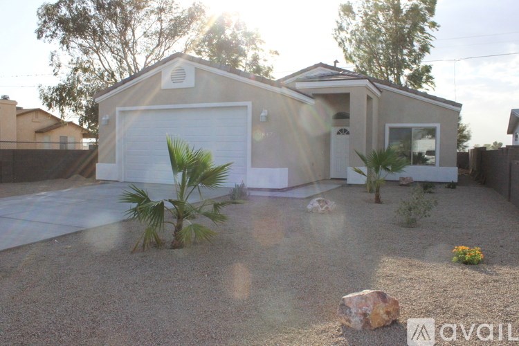 A house with a garage and a driveway with a rock and plants.