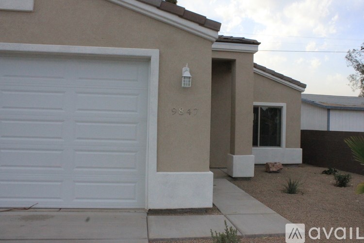 A house with a white garage door and the number 9947 on the wall.
