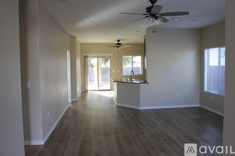 A spacious living room with a ceiling fan and hardwood flooring.