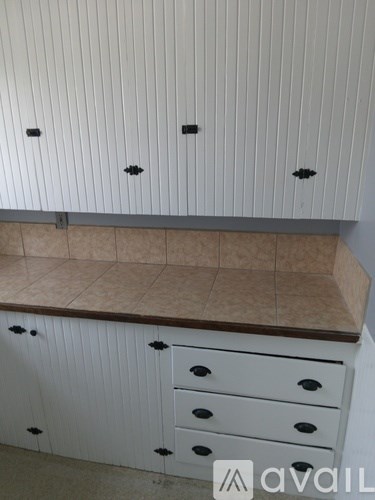 A kitchen with white cabinets and drawers and a counter top.