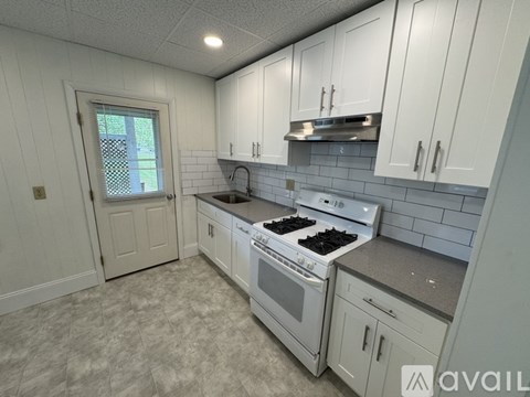 A kitchen with white cabinets and a stove top oven.